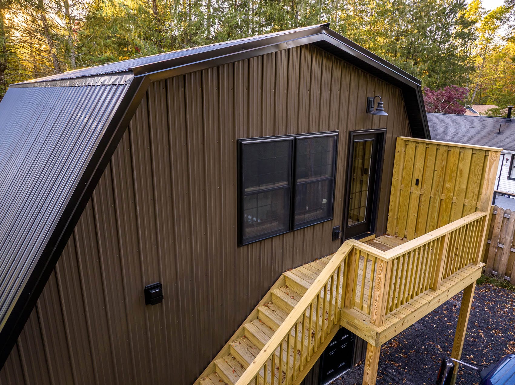 Aerial detail of brown gambrel garage with exterior deck and stair access