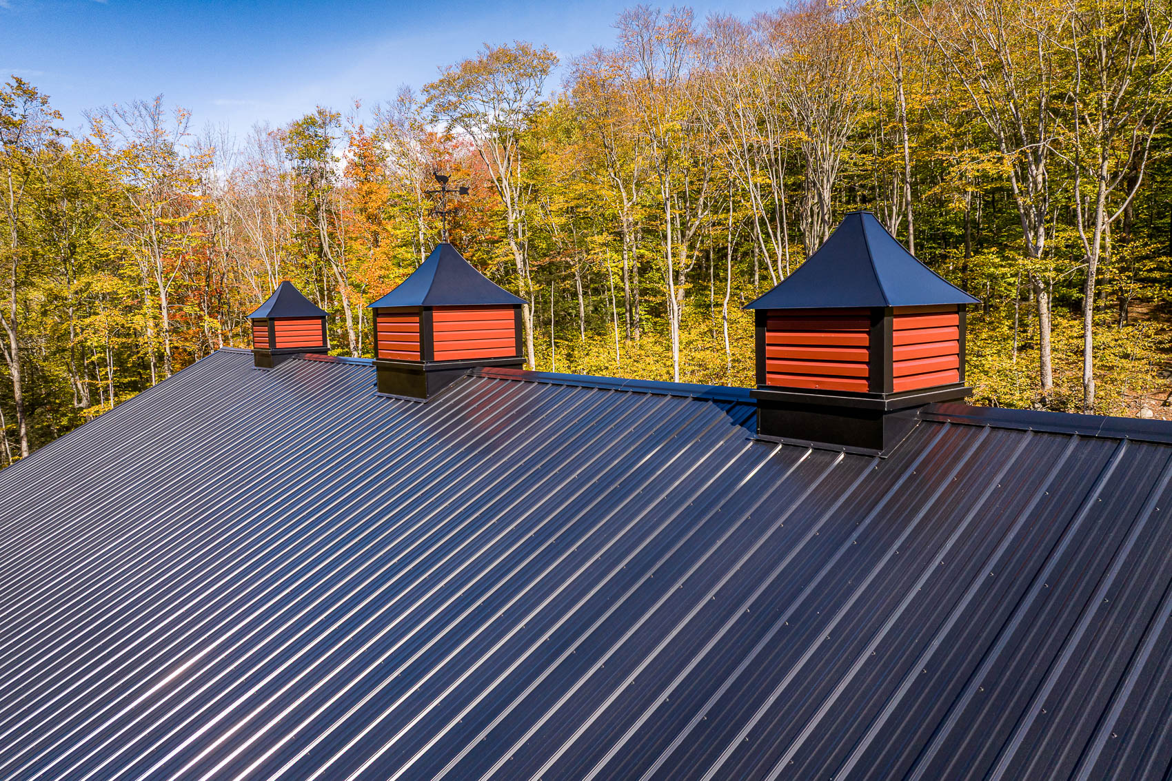 Black metal roof with red and black barn cupolas