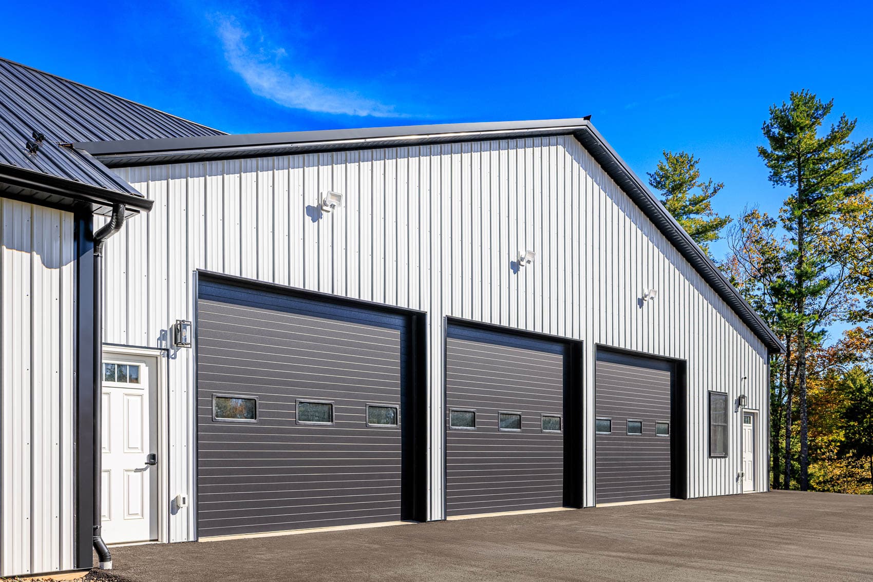 Close view of white pole building garage bays with black overhead doors
